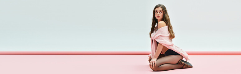 Beautiful young woman posing gracefully on a soft pink background in a modern artistic setting