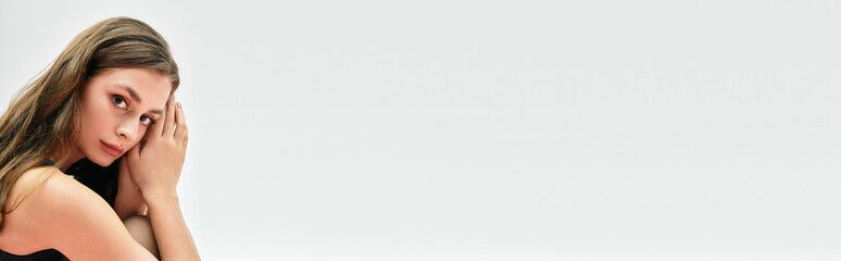 Obraz premium Captivating young woman showcasing beauty and elegance in a minimalist modern setting