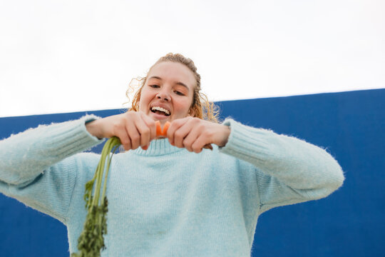 Woman having fun with vegetables outdoors in a playful manner