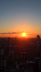 Fototapeta premium sun is setting over a city with tall buildings