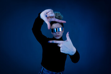 Person with curly hair wearing VR glasses posing in a studio with a futuristic theme