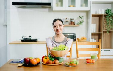  Young female in kitchen and writing down healthy recipe or daily ration diet at home. Active healthy clean eating