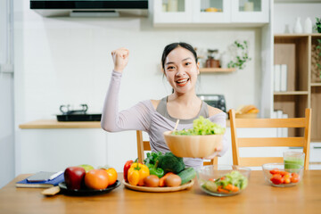  Young female in kitchen and writing down healthy recipe or daily ration diet at home. Active healthy clean eating