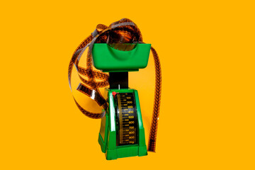 Vintage green food scale with negative film strip on yellow background