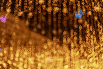 Golden and blurred lights create a bokeh effect with small hints of blue and purple scattered...