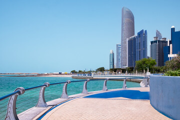 Corniche promenade in Abu Dhabi, UAE. Beautiful walkway in urban city park with green trees