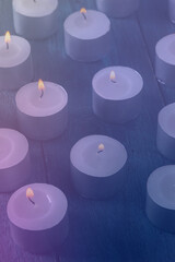 Tea light candles on a dark background, many lights in the dark, candlelight, toned image
