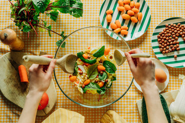 Woman preparing a summer salad with fresh vegetables indoors, top view