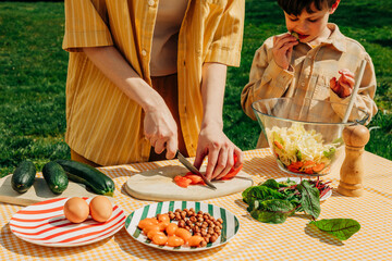 Mother and son preparing a healthy summer salad outdoors