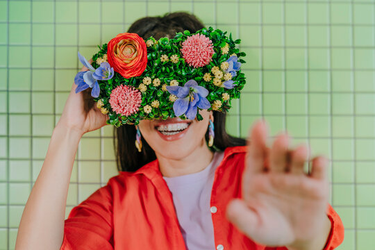 Woman wearing floral VR glasses smiling against a green background