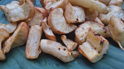 Traditional fried cassava pieces served on natural green banana leaves, the crunchy texture and golden color are typical of Indonesian food.