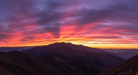 Vibrant Sunset over Majestic Mountain Range A breathtaking panoramic view of fiery colors painting the sky above a dramatic silhouette of peaks and valleys.