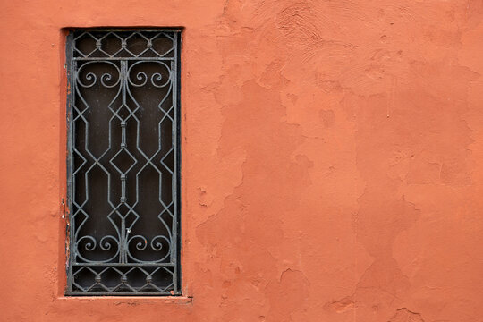 Decorative iron window on terracotta wall