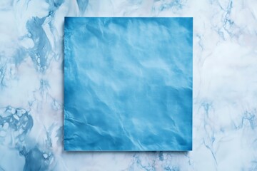 Textured blue sheet of paper with visible wrinkles lying on a marble surface, creating a minimalist backdrop