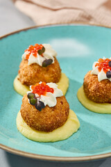 Gourmet Fish Croquettes on Creamy Potato Puree with Vibrant Garnish