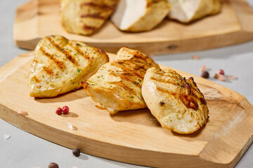 Grilled turkey medallions on wooden board, natural lighting, warm color mood, minimalist composition