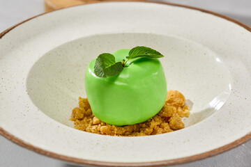 Glossy apple mousse pastry on textured biscuit crumble, minimalistic plating, vibrant daylight