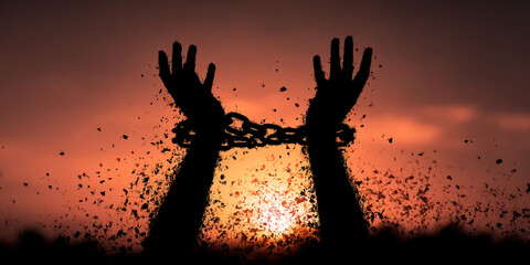 Silhouette of hands breaking free from chains against a sunset background, symbolizing liberation, freedom, and overcoming adversity