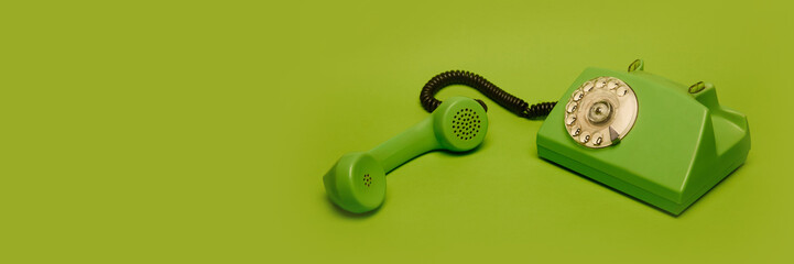 Old-fashioned green phone with rotary dial isolated on green background. Concept of retro...
