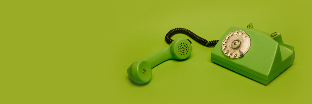 Old-fashioned green phone with rotary dial isolated on green background. Concept of retro aesthetics, vintage technology. Creative ad campaigns, nostalgia posters, banners