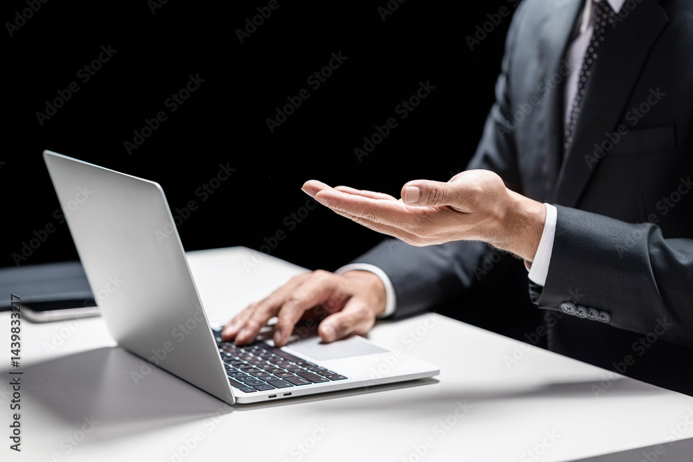 Poster businessman using a laptop while holding or showing something in his hand. cellphone and tablet on t