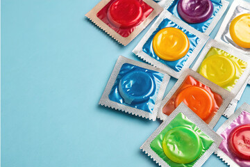 Colorful rainbow condom wrappers on blue pastel background, copy space. LGBT, LGBTQ+ safe sex protection contraceptive, wallpaper backdrop, fun vibrant condoms