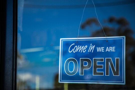 Blue come in we are open sign on glass shop door