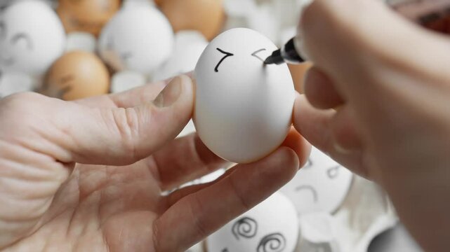 Hand drawing smiling face on white egg. Chicken happy egg. Cute eggs. Farm concept. Happy easter concept. Good mood. Close-up in 4K, UHD