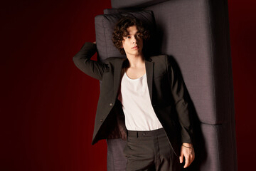 Stylish young man with curly hair poses in sleek black ensemble in modern studio setting