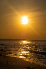 Calm ocean at sunset. Bright orange sun setting in the late evening. Bright path of light on the waves. Romantic seascape.