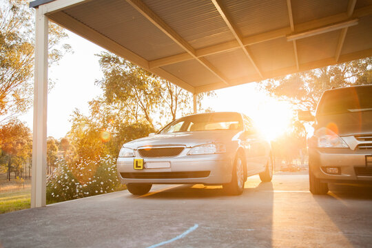 Car with L plate parked under carport with sun flare