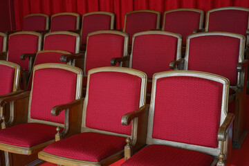 Empty rows of retro, old red theater or cinema seats. Old style, vintage chairs with red upholstery in concert hall.