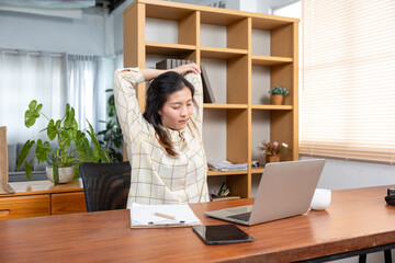 Young Asian female student feeling stressed exhausted stretching arms behind head during online...