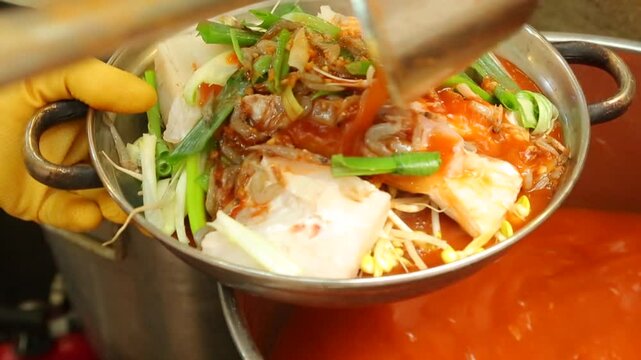 Spicy codfish stew being prepared with vegetables