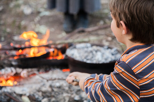 Young boy toasting a marshmallow on a campfire