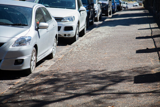 Parked cars stopped beside footpath in town