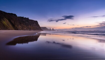 Fototapeta premium A serene coastal landscape at sunset with cliffs, calm waves, and a reflective sandy beach under a colorful sky.