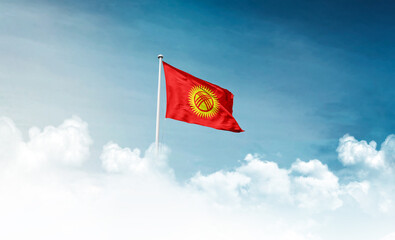 Naklejka premium Kyrgyzstan national flag with mast waving in beautiful sky. Kyrgyzstan flag for Republic Day and Independence Day.