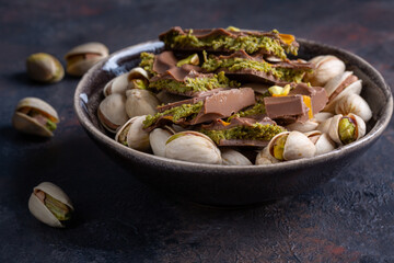 Dubai chocolate bar with filling made of kataifi (knafeh, kadayif) and pistachio  paste. Trendy chocolate on dark background.