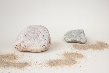 Rocks and sand on a light background. Minimalistic creative composite background for the presentation of cosmetics or products. Front view