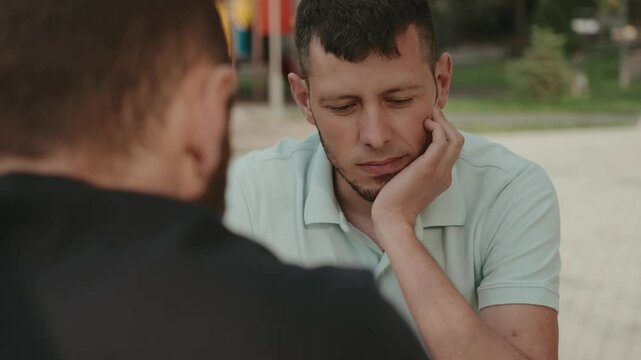 Two male friends sit together having a serious conversation. One friend is listening intently with a concerned expression. This video captures the emotions of friendship, empathy, and support.