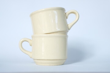 Stack of beige ceramic cups on white background. Reusable coffee cups are arranged in a balanced manner