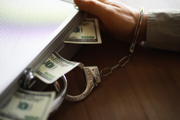 Handcuffed Person Holding Money-Filled Briefcase, Concept of Financial Crime and Corruption