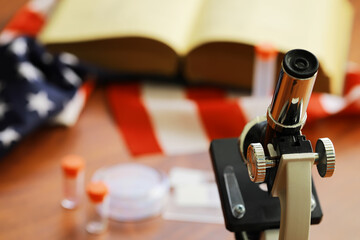 Microscope and Laboratory Equipment with American Flag and Open Book in Background