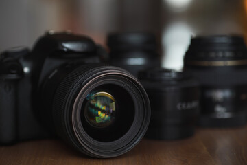 Close-Up of DSLR Camera Lens with Additional Lenses on Wooden Surface