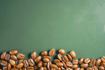 A display of roasted coffee beans scattered on a green background.