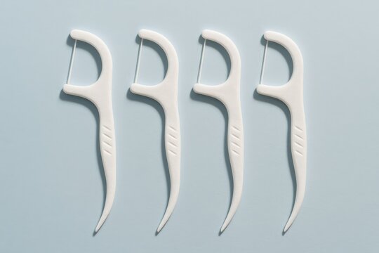 Minimalist Arrangement of White Dental Flossers on Blue Background, showcasing oral hygiene and dental care product on a clean, simple composition.