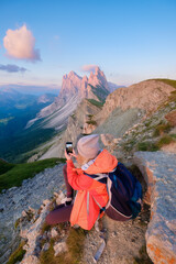 Girl sitting on top of mountain taking pictures of landscape. Girl with backpack for mountain hiking. Mountain landscapes in summer. Place for mountain weather, travel and vacation.