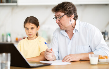 Obraz premium Little daughter shows her father how to use laptop