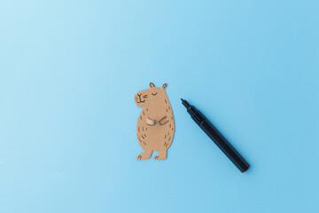 step in creative project, top down view of Handmade cardboard capybara against light blue...